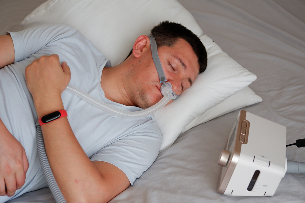 Młody mężczyzna śpiący z aparatem CPAP - bezdech-senny.info.pl